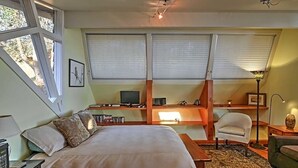 A bedroom with a large bed, a desk with a computer, and a chair. There are windows with blinds, a lamp, and a picture on the wall. - Studio with a View!! (Friday Harbor)