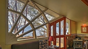 A cozy room with a large window offering a view of the outdoors, a wooden door, and a small table with a lamp. - Studio with a View!! (Friday Harbor)