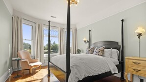A four-poster bed with a white bedspread, a chair, a bedside table, and a lamp. - The Arabella House - Charmed Victorian in Historic Downtown Ventura (Ventura)