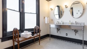 A bathroom with a large window, two mirrors, a sink with multiple faucets, and a chair with towels. - The Arabella House - Charmed Victorian in Historic Downtown Ventura (Ventura)