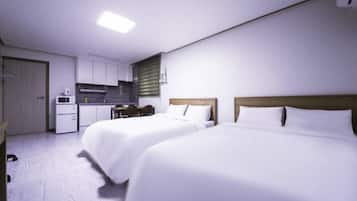 A hotel room with two beds, a kitchenette, and a small dining area.
