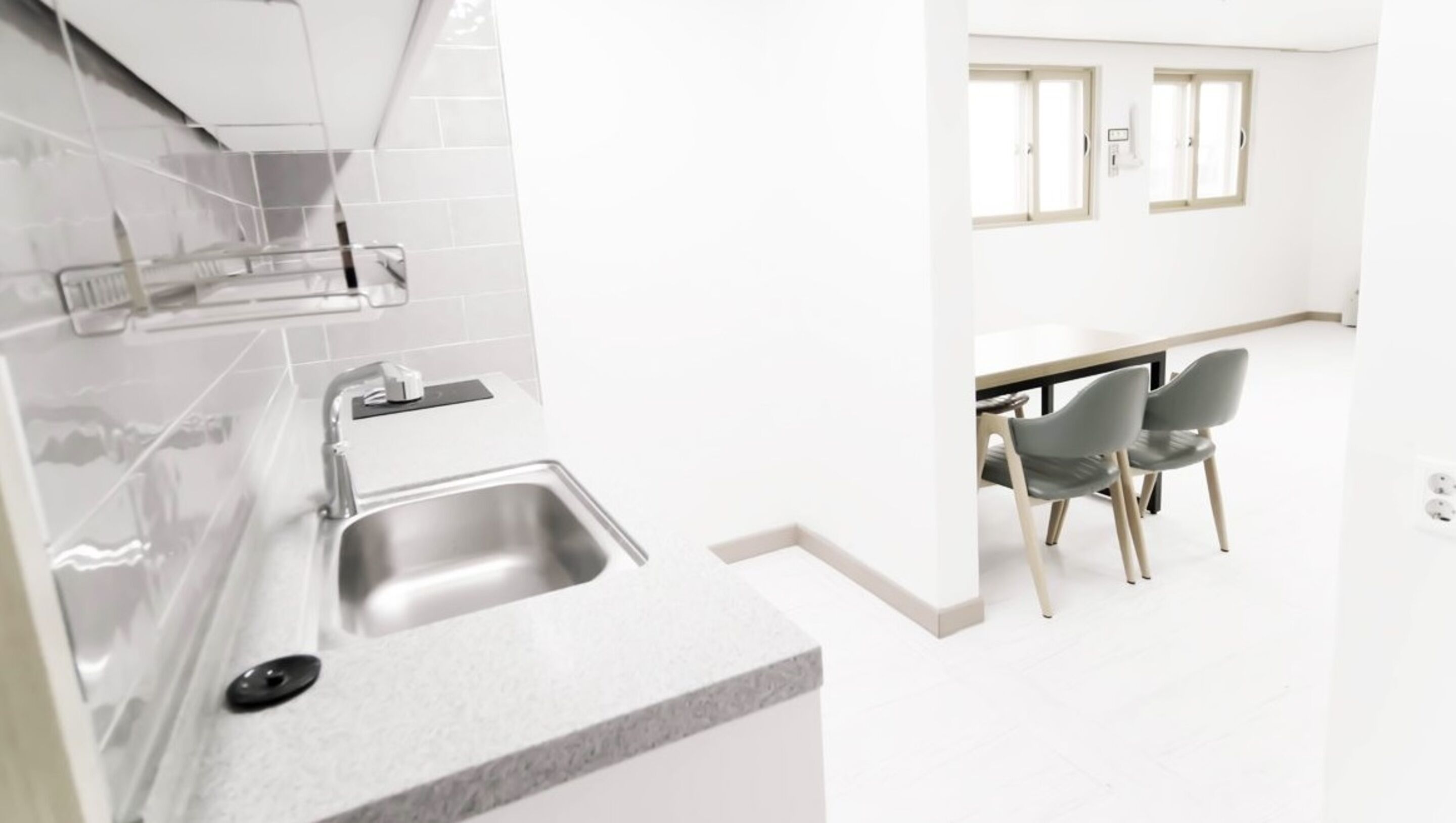 A modern kitchen with a stainless steel sink, a countertop, and a window above the sink.