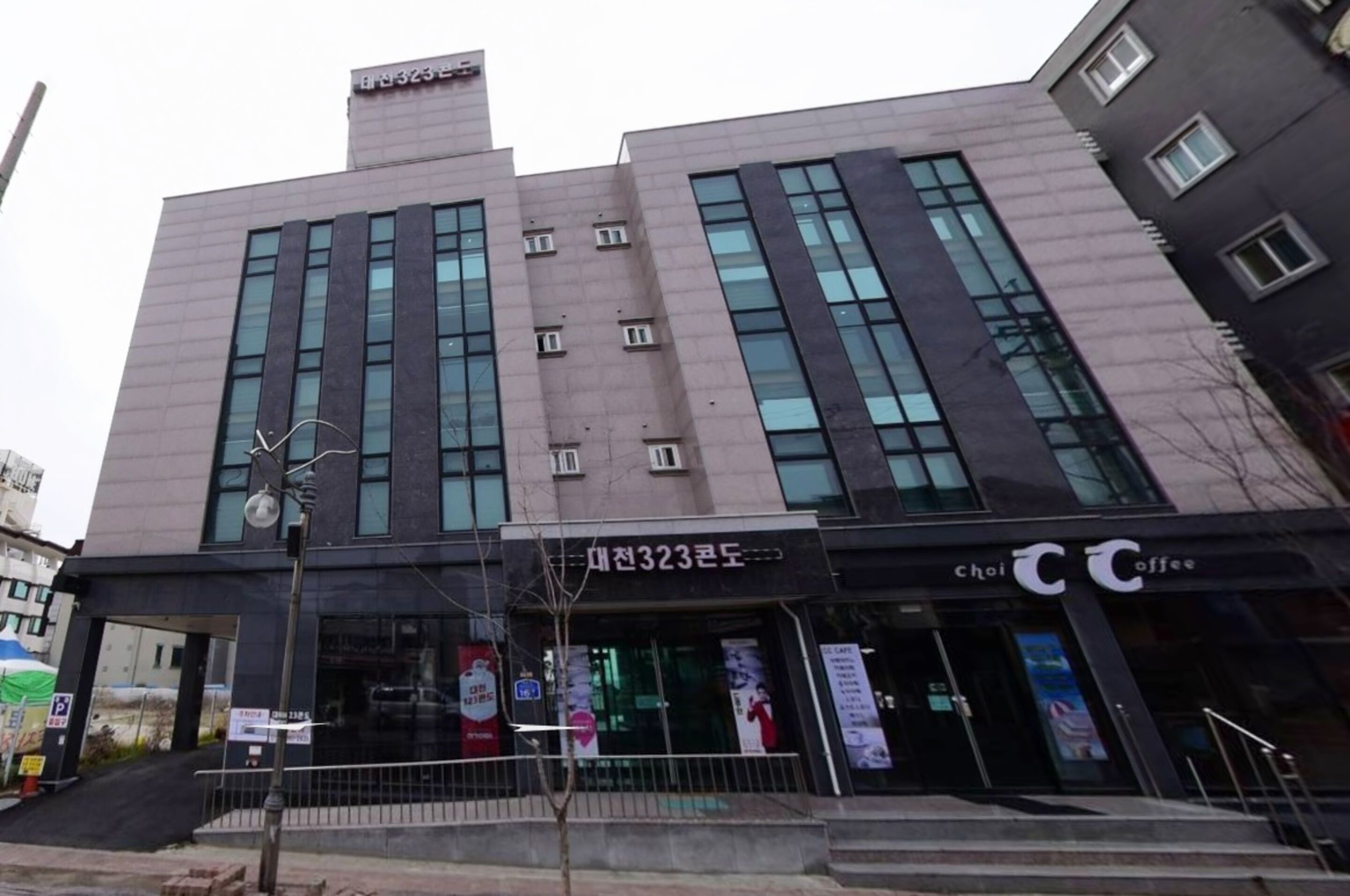 A modern building with a large entrance, signage for 'Choi Coffee', and a visible address 'No. 323'.