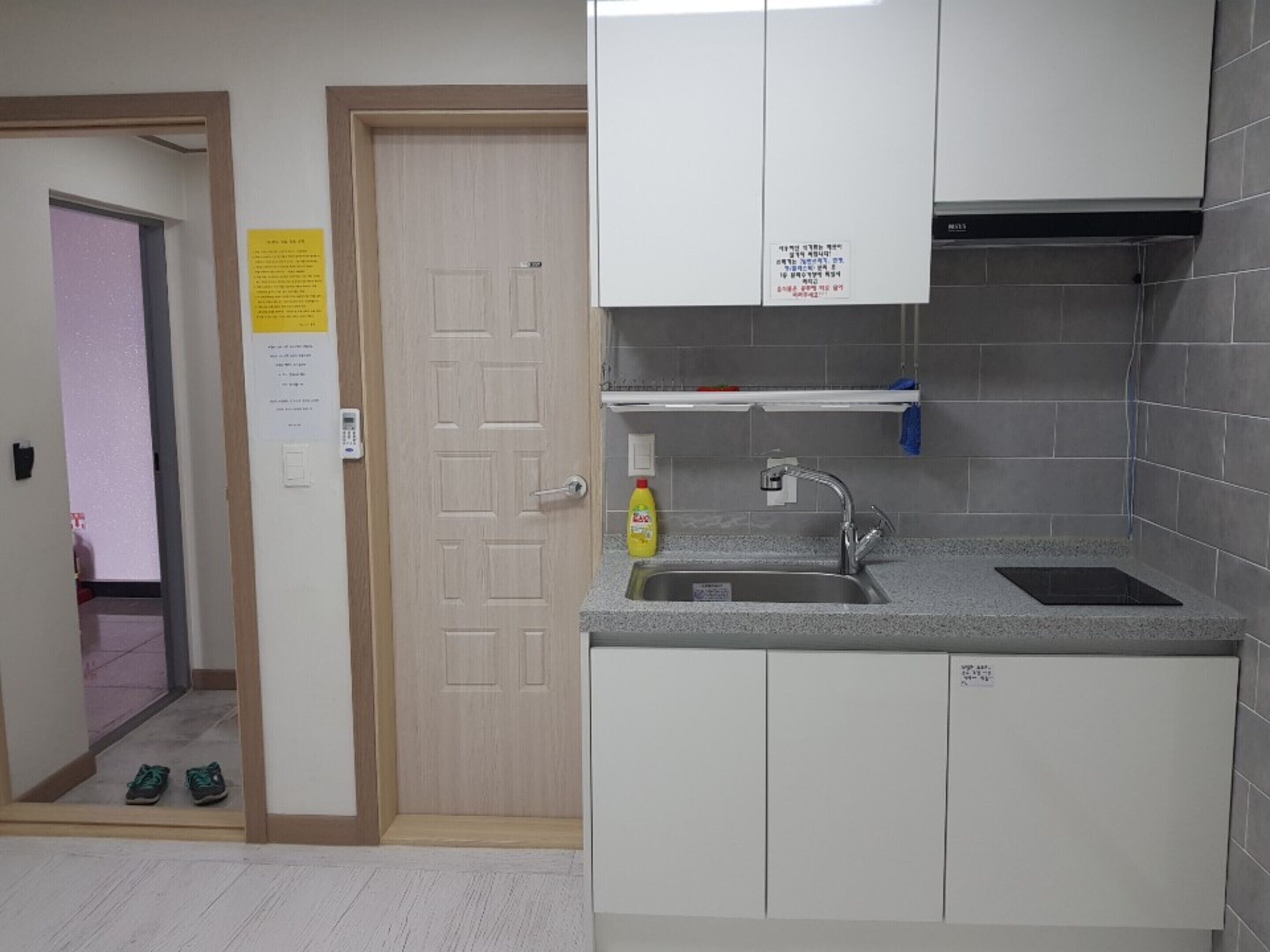 A kitchen with white cabinets, a stainless steel sink, and a yellow bottle of dish soap.
