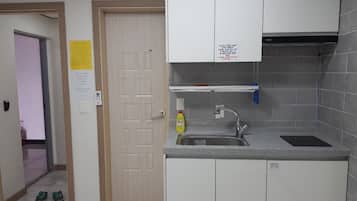 Una cocina con armarios blancos, un fregadero de acero inoxidable y una botella amarilla de detergente.