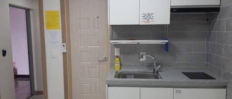 A kitchen with white cabinets, a stainless steel sink, and a yellow bottle of dish soap.