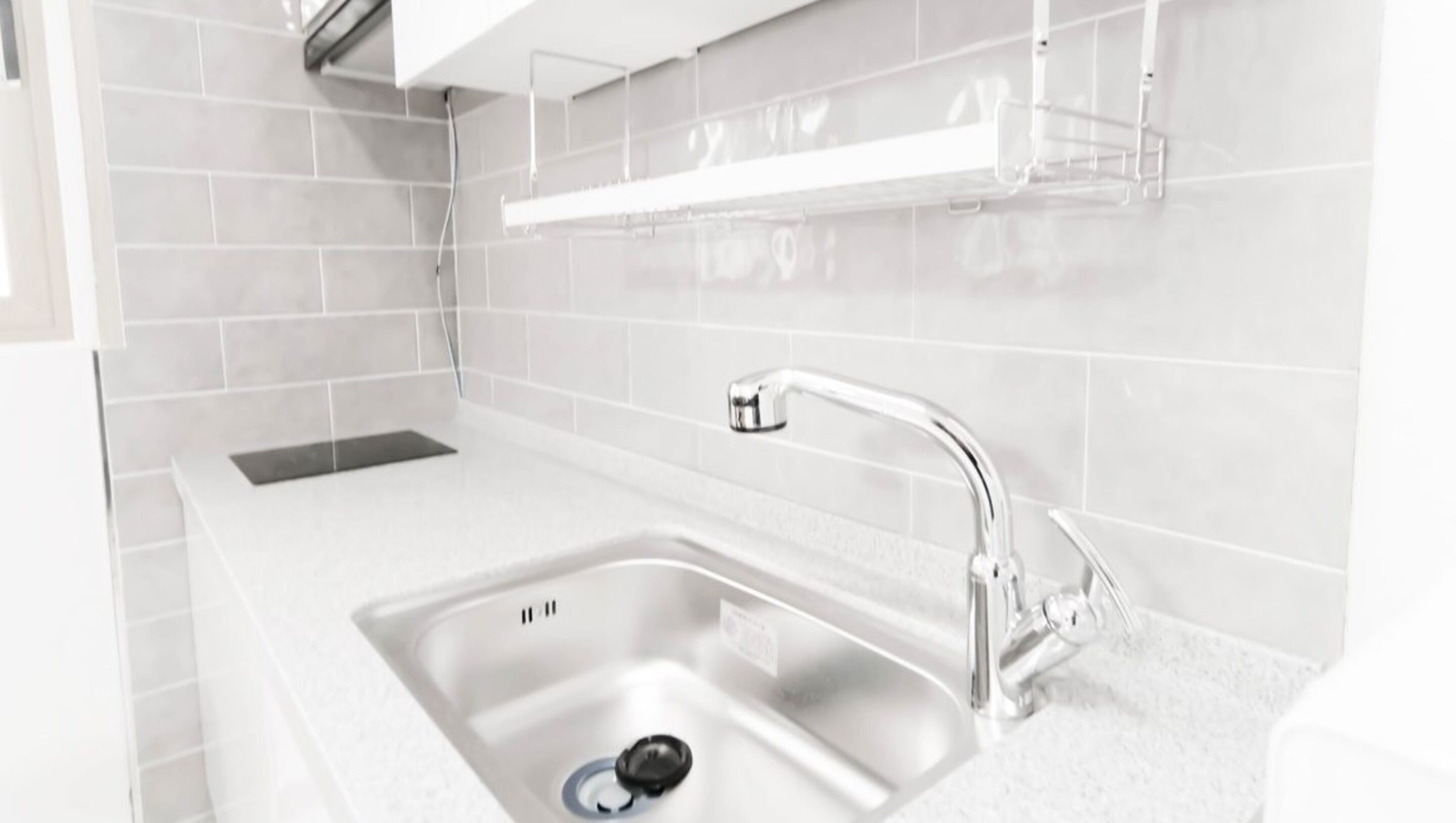 Een moderne keuken met een wit aanrecht, een RVS spoelbak en een chromen kraan.