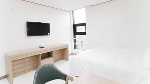 A modern hotel room with a bed, a desk, and a TV mounted on the wall. - Daecheon 323 Condo (Boryeong)