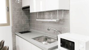 A kitchen with a double sink, a microwave, and a stainless steel faucet. - Daecheon 323 Condo (Boryeong)