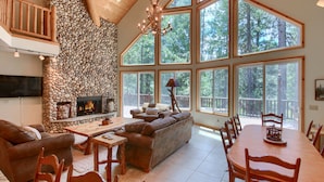 Un salón espacioso con chimenea de piedra, ventanas amplias y techo alto.