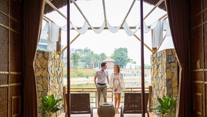 A couple standing in a semi-open room with stone walls and a view of a lake. - Memorina Ninh Binh Resort (Tay Hoa Lu)