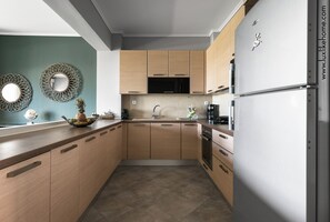 A modern kitchen with wooden cabinets, a stainless steel refrigerator, and a built-in oven.