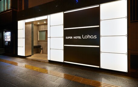 A Super Hotel Lohas with a modern facade, a visible entrance, and a vending machine outside.