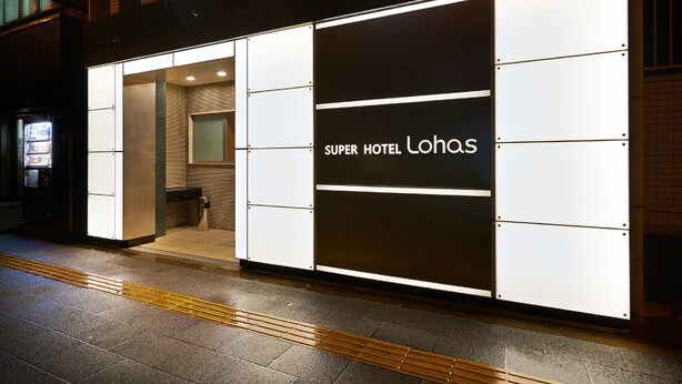 Le Super Hotel Lohas se distingue par sa façade moderne, son entrée bien visible et un distributeur automatique situé à l’extérieur.