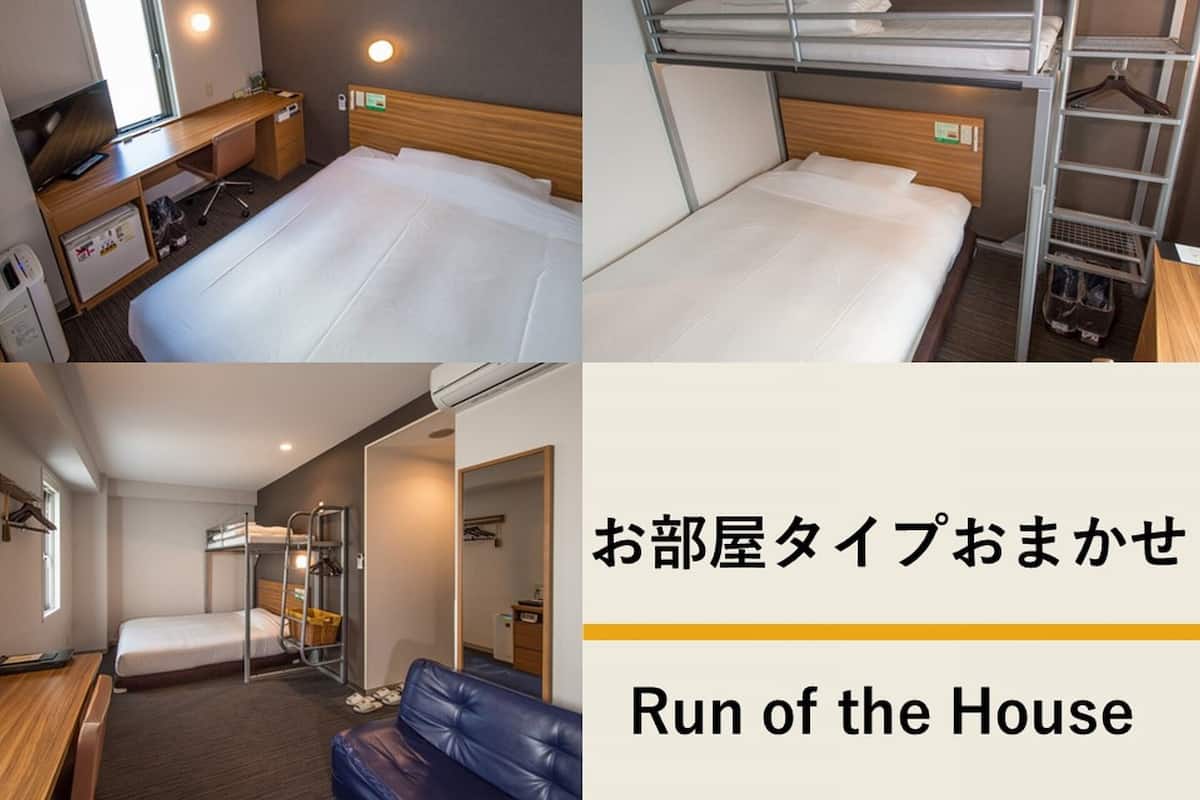 Een hotelkamer met een stapelbed, een bureau met stoel, een klein tafeltje, een bank en een spiegel.