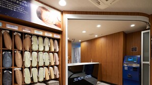 Un espace d’accueil d’hôtel comprenant un comptoir de réception, un kiosque d’enregistrement numérique et un mur où sont exposés différents oreillers et couvertures.