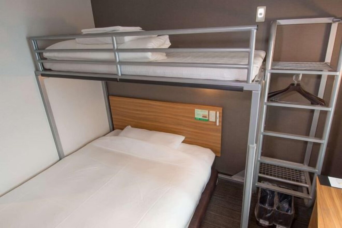 A bunk bed with a wooden headboard, a metal shelf unit with a hanging rack, and a small shoe rack.