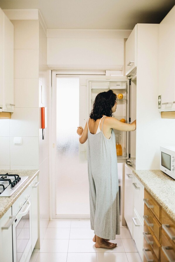 Une cuisine avec des meubles blancs, un four à micro-ondes et une cuisinière à gaz.