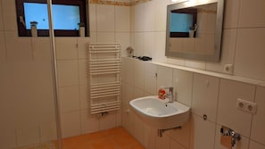 A bathroom with a sink, mirror, towel rack, and a window with a view.