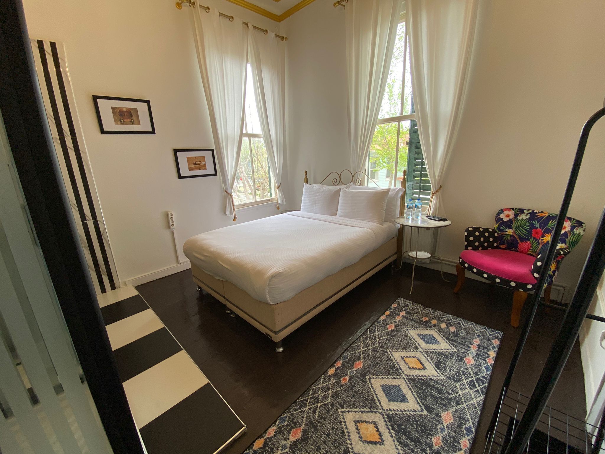 A bedroom with a bed, a chair, a small table, and a window with curtains.