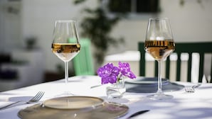 A table set for two with wine glasses, a plate, and a small vase with purple flowers. - No16 Ada  (Adalar)