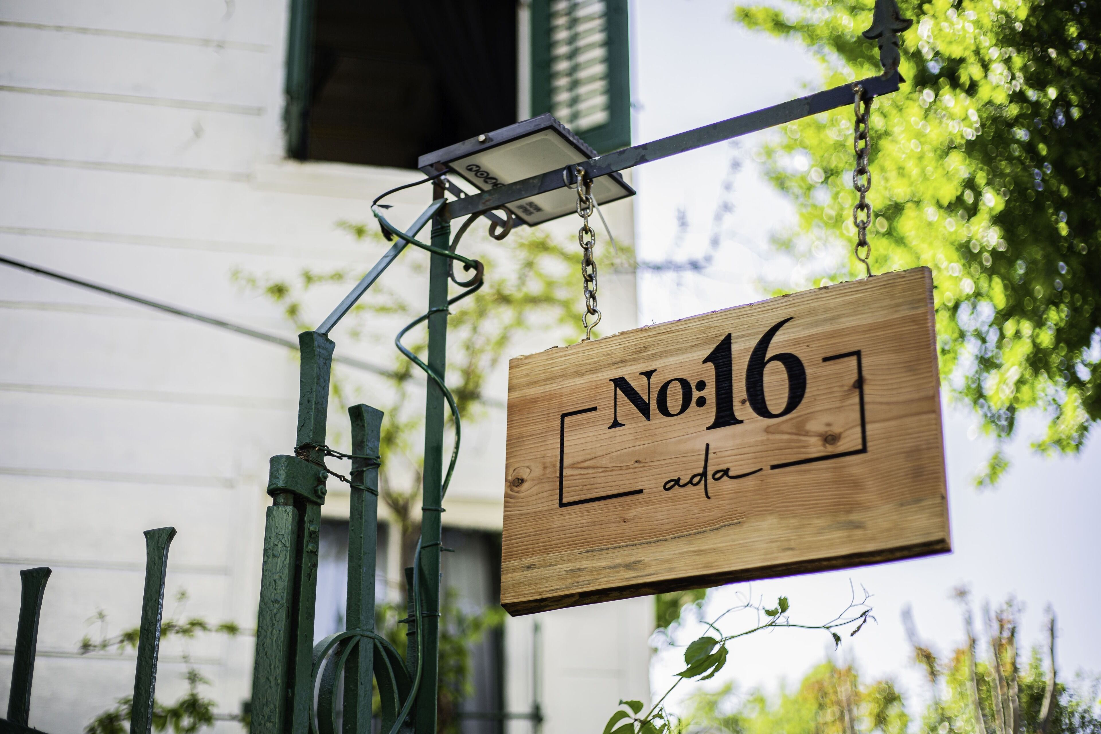 A wooden sign with the number 16 and the word "ada" on it, hanging from a metal structure.