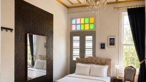 A bedroom with a large bed, a chandelier, a mirror, a window with curtains, and a small table with a lamp. - No16 Ada  (Adalar)