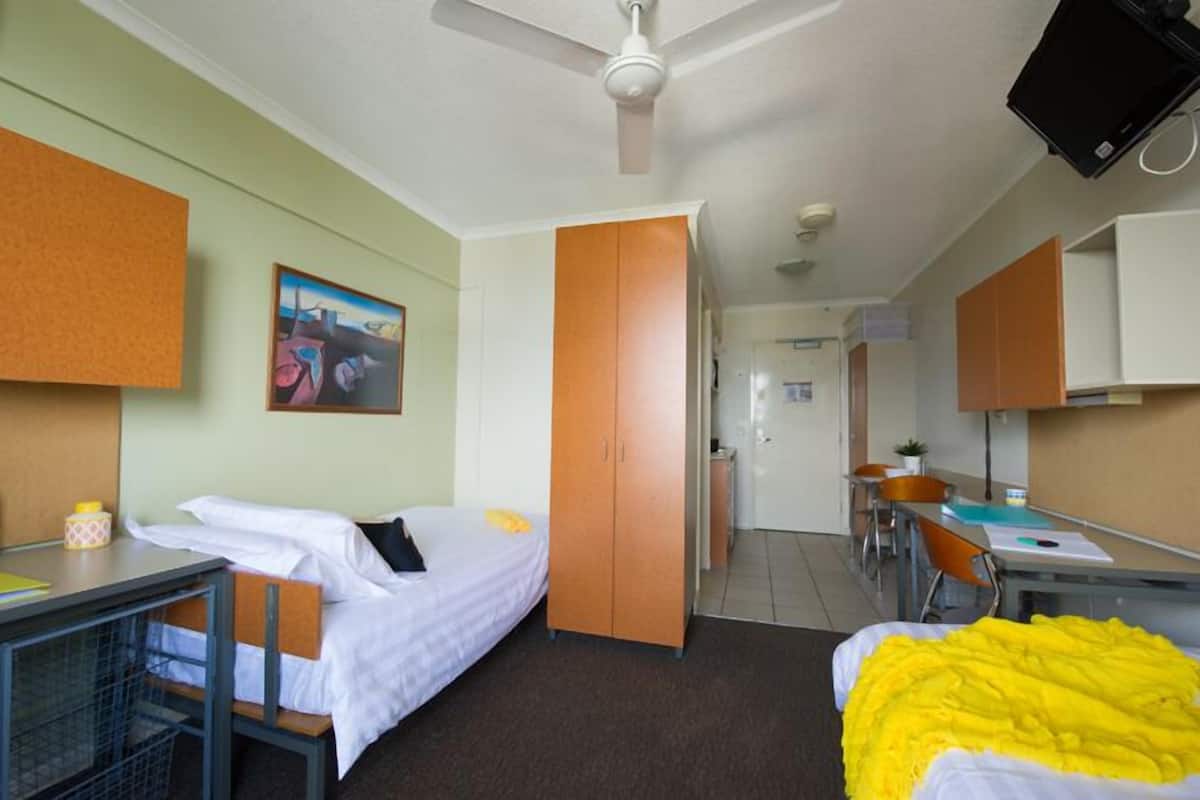 Une chambre d’hôtel avec un lit, un bureau, une armoire et un tableau au mur.