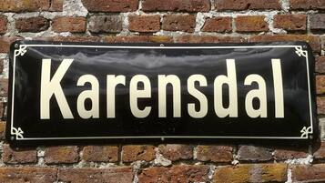 Un letrero negro con la palabra 'Karensdal' en letras blancas sobre un muro de ladrillo.