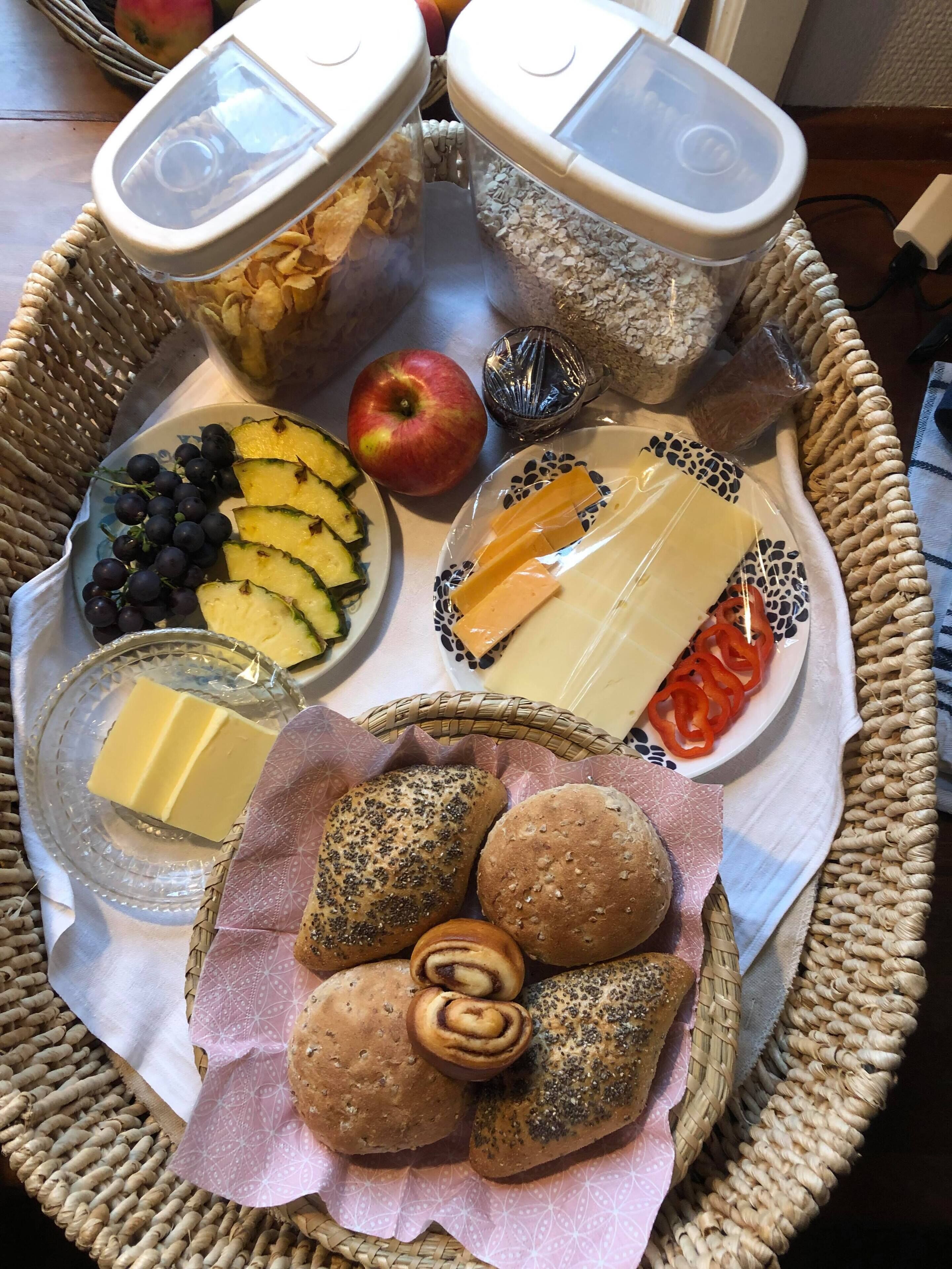 A wicker tray with various food items including cheese, bread, and fruits.