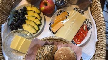 A wicker tray with various food items including cheese, bread, and fruits.