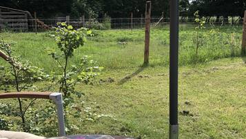A garden with a tiled table, a metal chair, and a metal umbrella.
