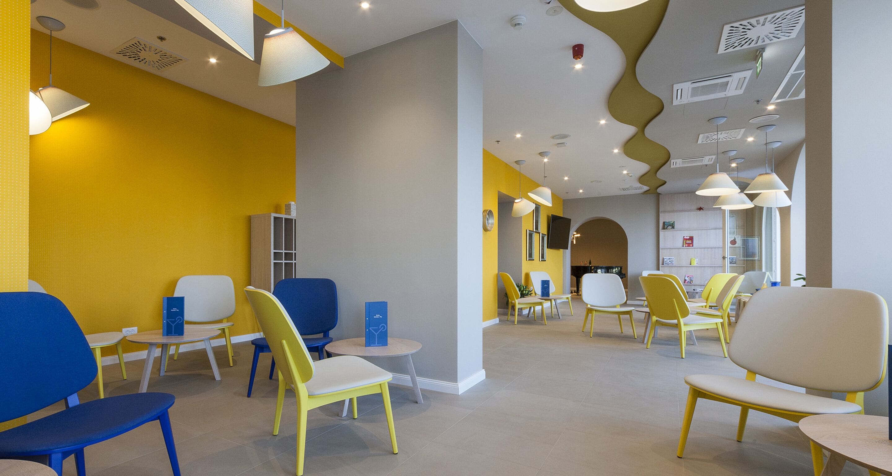 Un intérieur moderne avec des chaises jaunes et bleues, une table ronde et un design de plafond original.