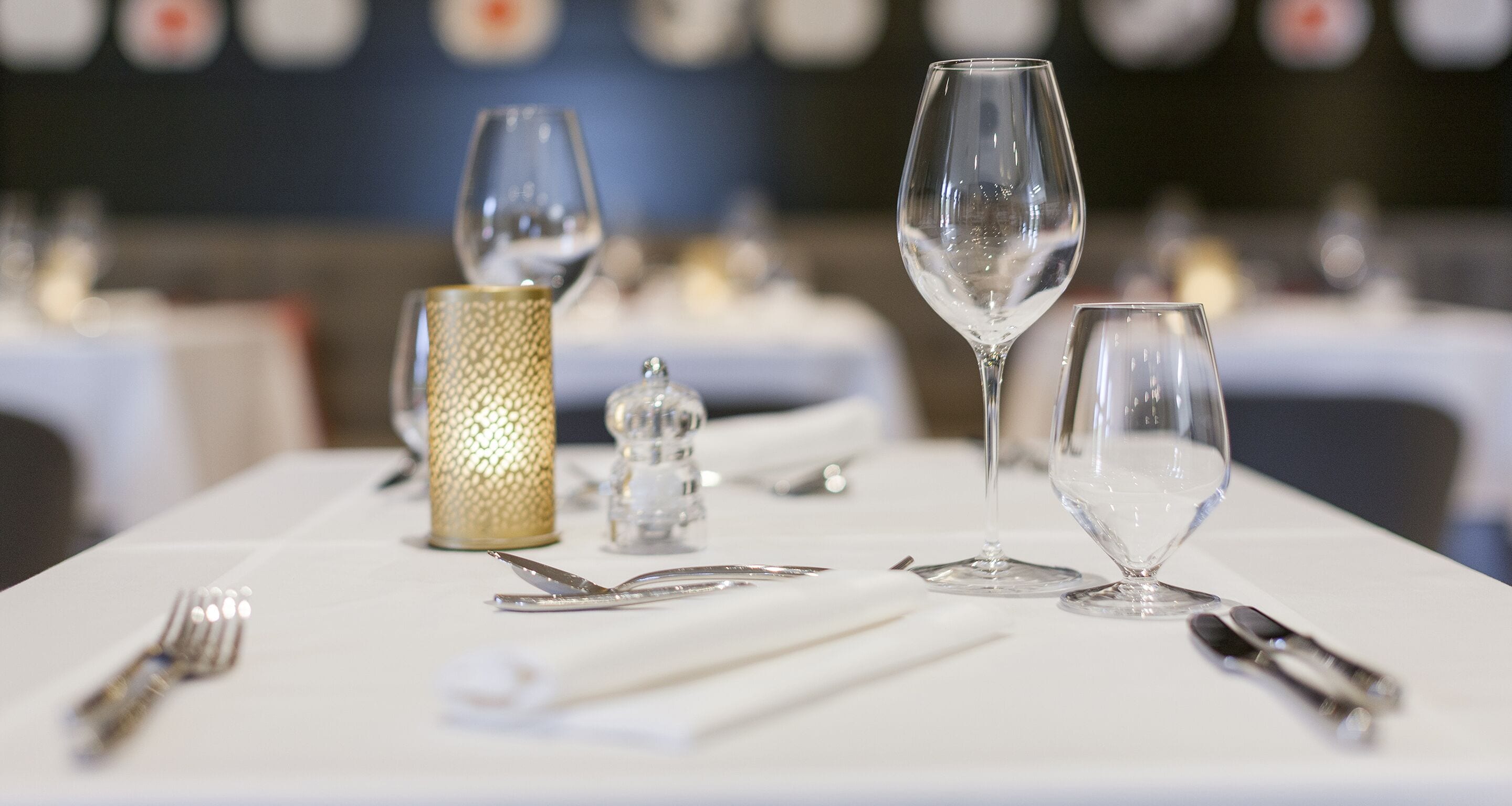 A table set with wine glasses, cutlery, and a decorative candle holder.