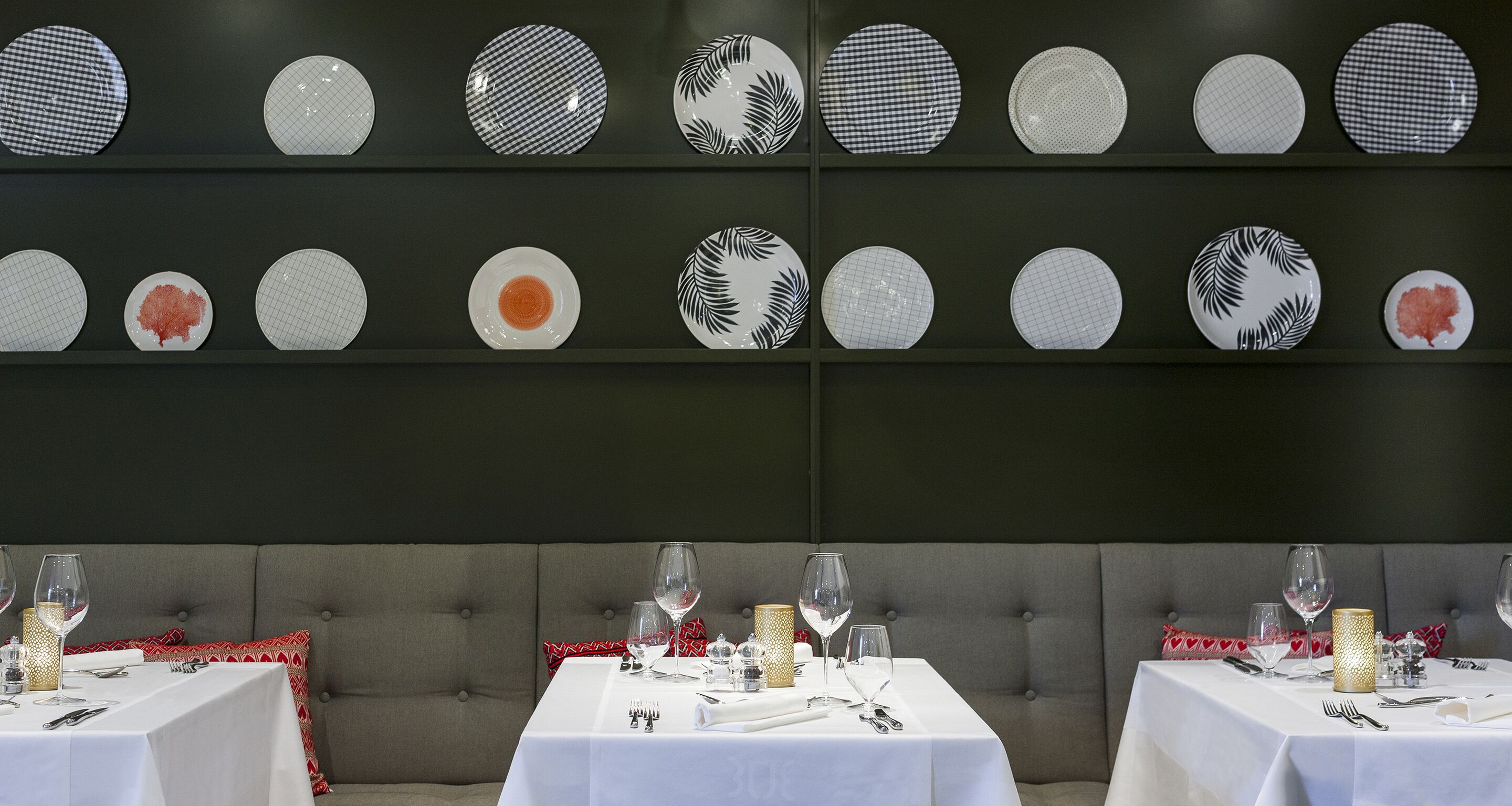 A restaurant with a wall of plates and a table set for dining.