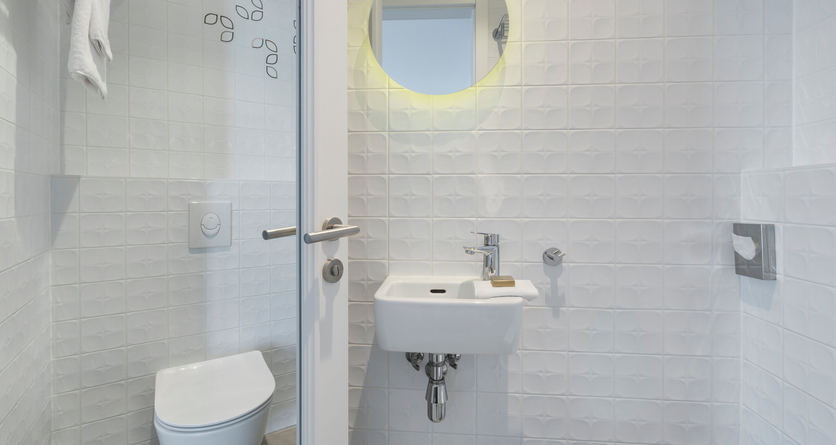 A bathroom with a toilet, a sink, and a glass shower door.