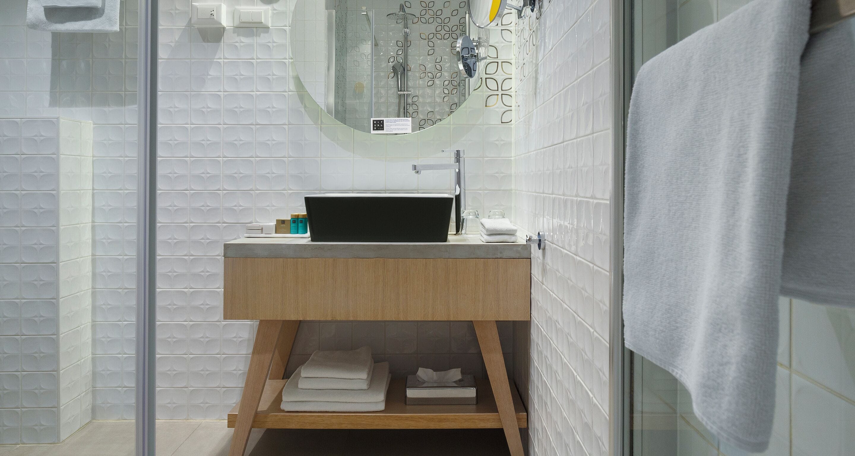 Ein modernes Badezimmer mit einer Duschkabine aus Glas, einem Holzboden und einem Spiegel über dem Waschbecken.