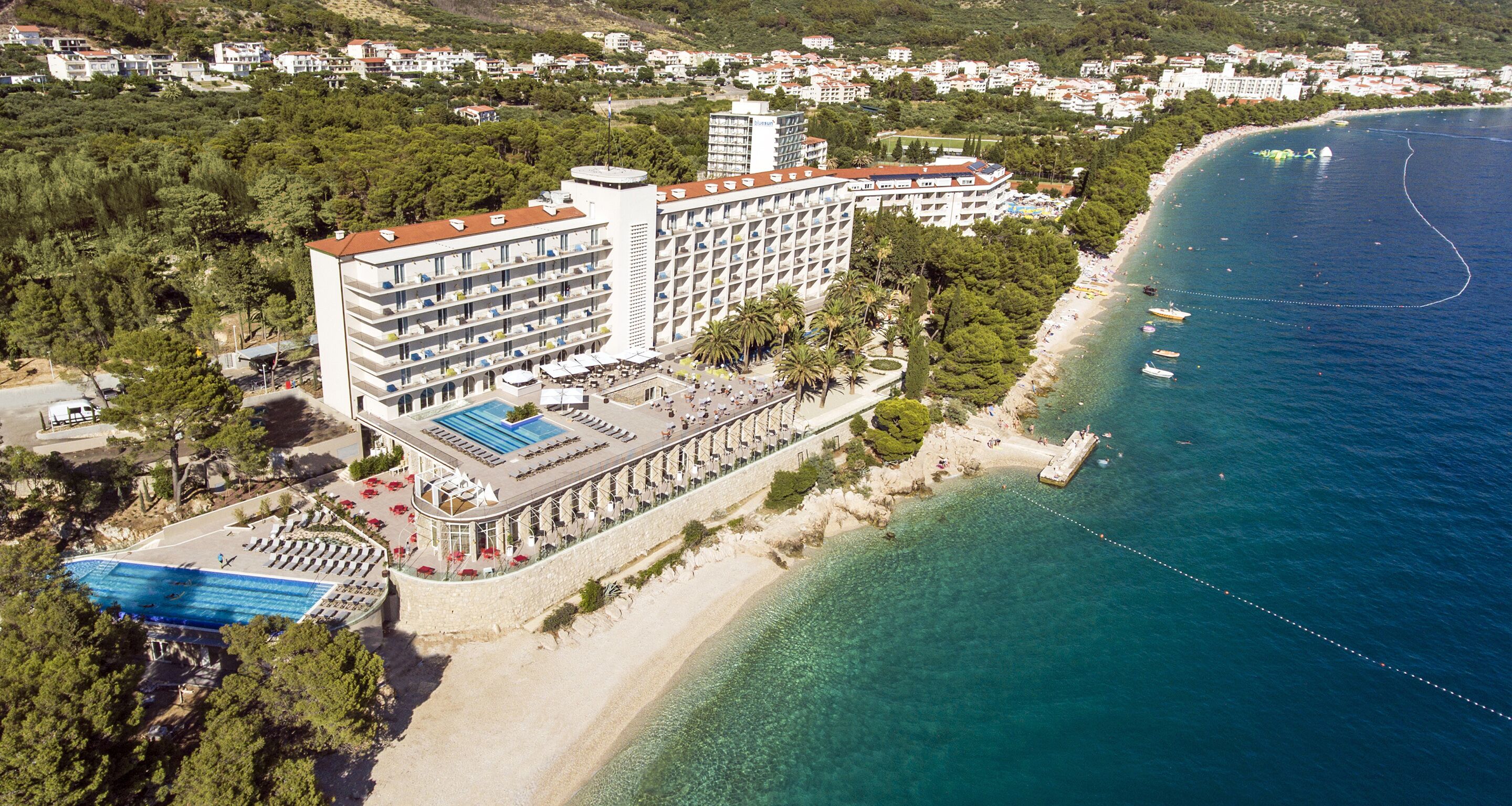 Vue aérienne d’un hôtel situé sur la côte, doté d’une piscine, d’un accès à la plage et offrant une vue sur la mer.