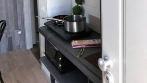 Una cuina moderna amb taulell negre, una olla a la cuina i ampolles de vi a l'estant superior.