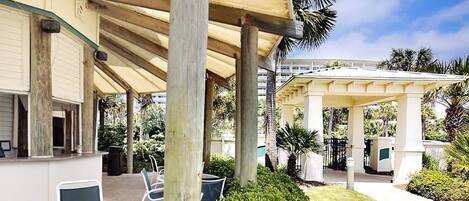 A covered outdoor area with a pergola, seating, and a well-maintained lawn.