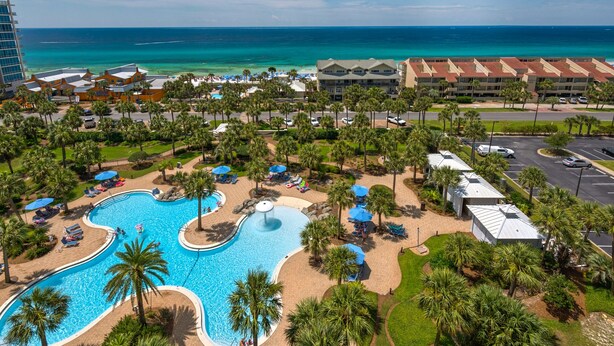 A resort with a large swimming pool, palm trees, and a view of the ocean. - Gulf Views~Steps2Beach~FAB Lagoon Pool~2BR Sterling Shores 916 (Destin)