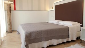 A modern bedroom with a large bed, a bedside table, and a floor lamp. - Bilocale Mameli - With balcony (Verona)