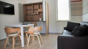 A compact living space with a kitchenette, a dining area, and a seating area. - Bilocale Mameli - With balcony (Verona)
