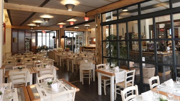 A restaurant with wooden beams, large windows, and tables set for dining. - Bilocale Mameli - With balcony (Verona)