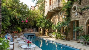A poolside area with a stone building, outdoor seating, and a clear pool. - Arthaus Beirut (Beirut)