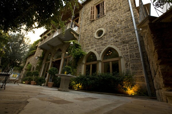Un edificio de piedra con ventanas de arco y una fuente en el patio.