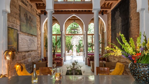 A spacious lobby with high ceilings, arched columns, and large windows allowing natural light. There are comfortable seating areas and a central decorative fountain. - Arthaus Beirut (Beirut)