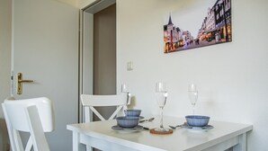 A dining area with a white table, two blue bowls, two wine glasses, and a door with a brass handle. - Rimmler - Südstrandperle (Sylt)