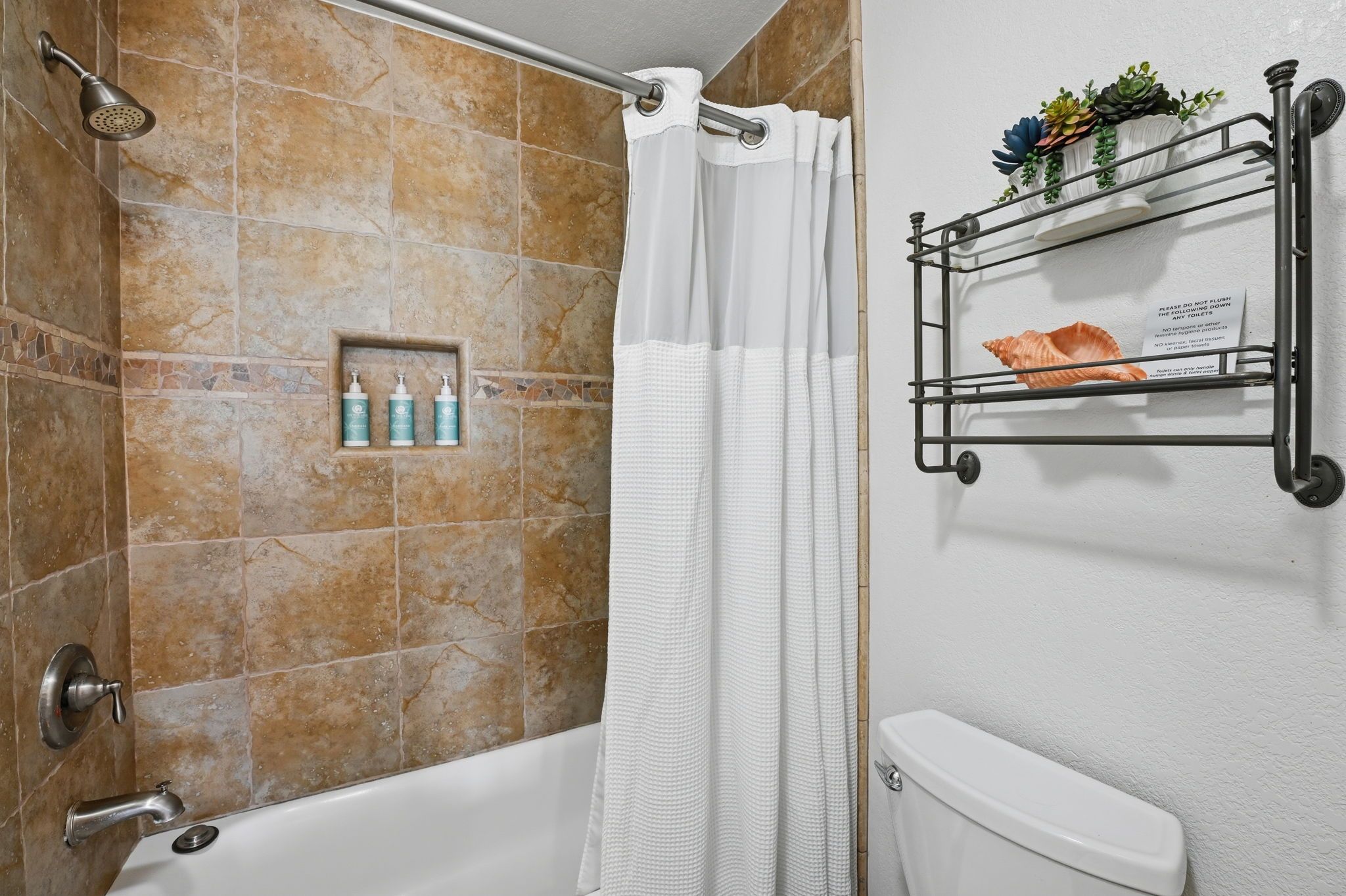 Une salle de bain équipée d’une douche, de toilettes, d’un porte-serviettes et d’une étagère pour les articles de toilette.