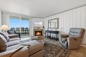 A living room with a fireplace, a sofa, a chair, and a table.